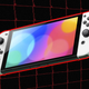 An OLED Switch hangs in the air in front of a red wire grid.